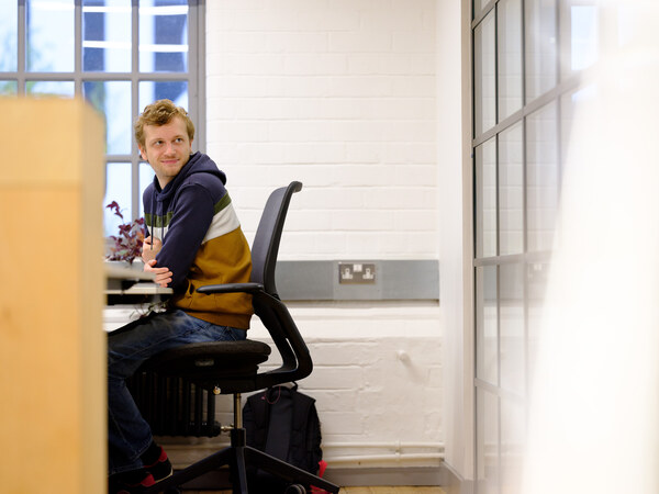 Man sat on chair in office smiling