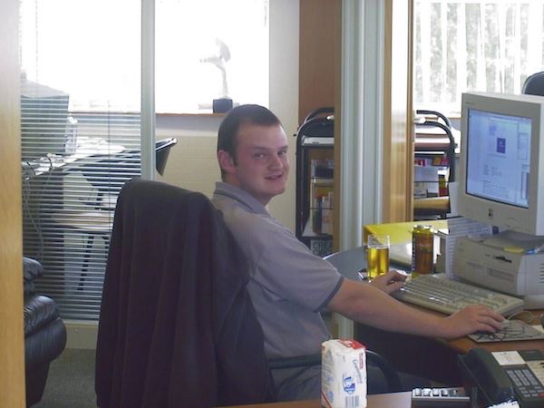 A fresh-faced Gaz, sometime back in the 1990s, sitting at a desk with a keyboard and a vintage Apple computer monitor on it.