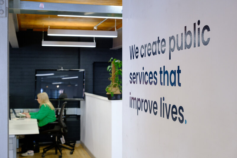 An office with 'We create public services that improve lives' written on the wall
