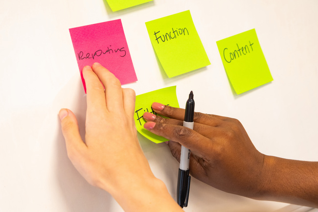 Two hands placing post it notes on a wall