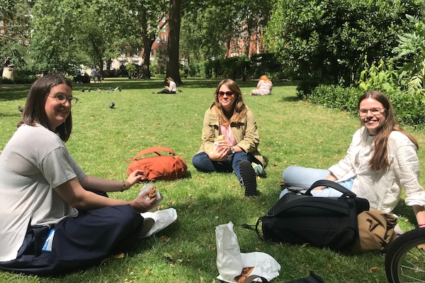 3 members of dxw's design team sitting on the grass in a park having their lunch