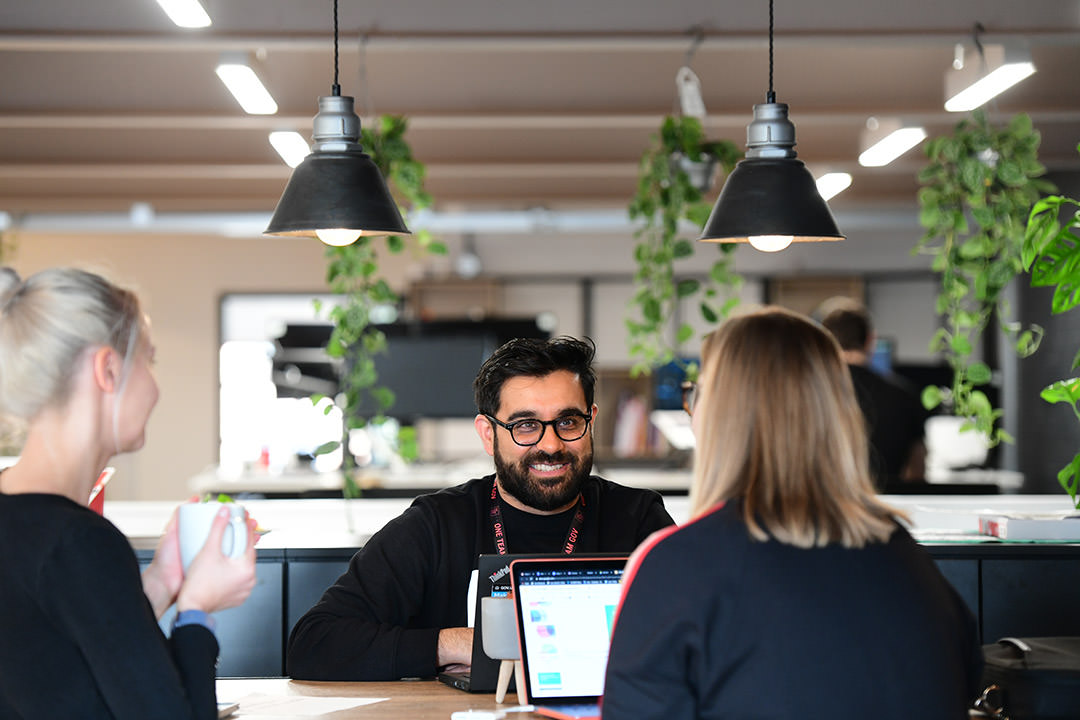 People having a discussion in a meeting with laptops