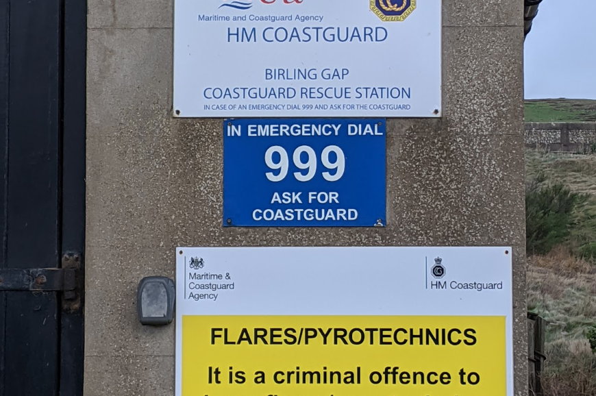 Signage saying dial 999 and ask for the Coastguard at a Coastguard rescue station