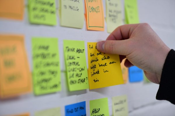 A person sticking a post-it note to a wall