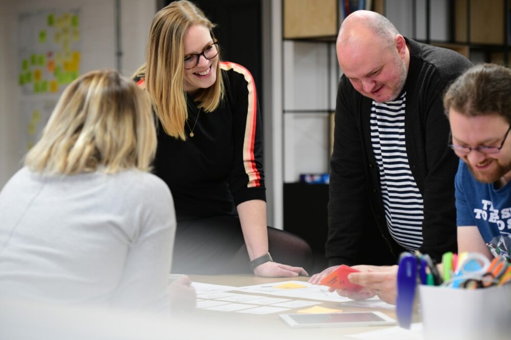 3 people in a meeting looking at a chart on a table