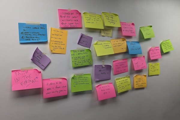 A wall covered with post-its with feedback about  the unconference on it.