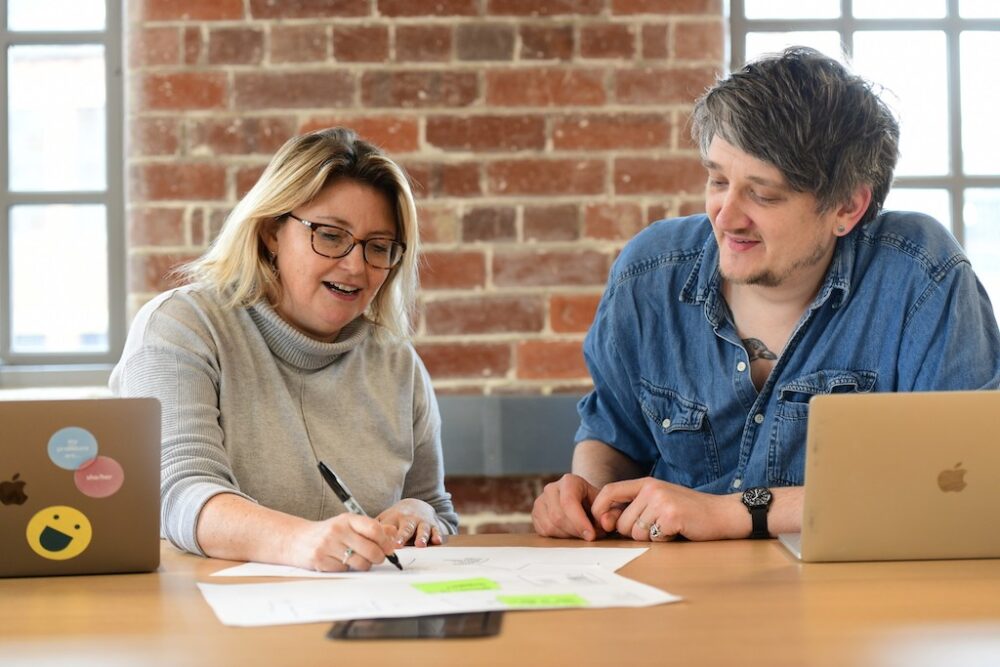 2 people in a meeting writing on post its