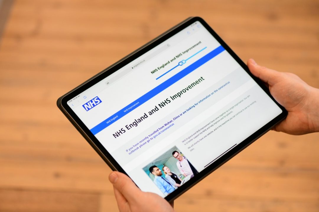 A person showing the NHS website on a tablet